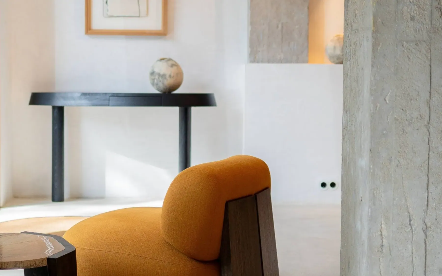 The Espai Rö showroom in Barcelona: a dark console table, a plaster sphere and a mustard armchair in low afternoon light.