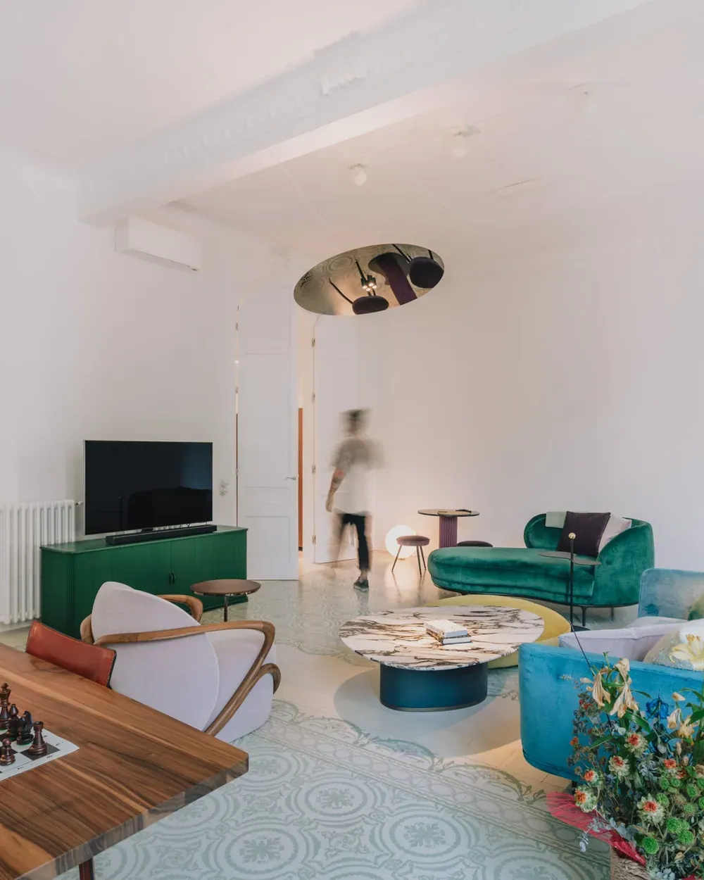 A living room by Espai Rö with a low blue sofa, a sculptural floor lamp and a chess table.