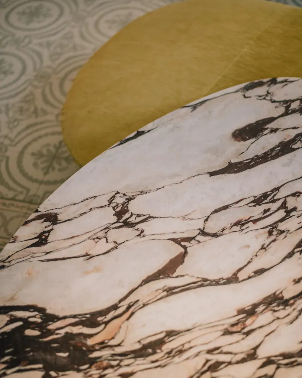 A close view of a marble table top with dark veining against a pale plaster wall.